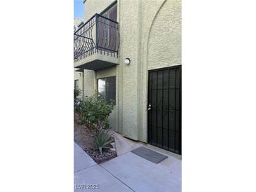 Light green stucco building with a balcony and security door at 7084 Burcot Ave # G24, Las Vegas, NV 89156