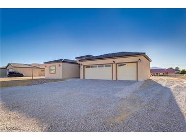 Contemporary home featuring a large garage, neutral tones, and modern lighting fixtures for a welcoming facade at 2140 Upland Ave, Pahrump, NV 89048