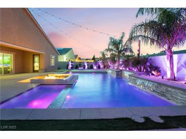 Luxury pool with waterfall feature and fire pit at sunset at 5260 Brayden Ct, Las Vegas, NV 89131