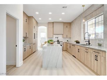 Modern kitchen with light wood cabinets, marble island, and stainless steel appliances at 5737 Heather Breeze Ct, Las Vegas, NV 89141