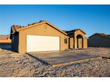 Tan stucco home with white garage door and arched entryway at 5821 Genoa Ave, Pahrump, NV 89060