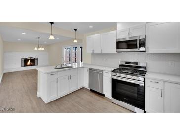 Modern white kitchen featuring stainless steel appliances and a breakfast bar at 6436 Whippoorwill Way, Las Vegas, NV 89103