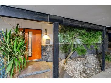 Mid-century modern home with an orange door and stone accents at 1558 Aztec Way, Las Vegas, NV 89169