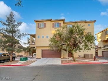 Tan three-story townhome with attached garage and landscaping at 5965 Palmilla St # 2, North Las Vegas, NV 89031