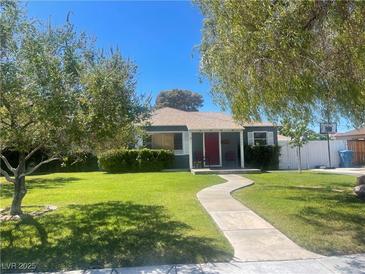 Ranch style home with red door, landscaped lawn, and walkway at 1206 Douglas Dr, Las Vegas, NV 89102