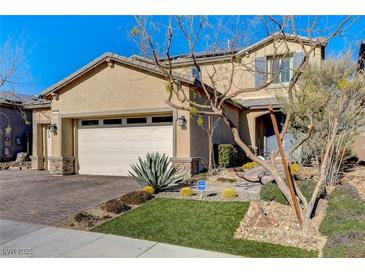 Two-story home with desert landscaping, stone accents, and a paver driveway leading to a two-car garage at 1610 Dire Wolf Avenue, North Las Vegas, NV 89084