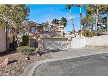 Two-story house with a tan exterior, two-car garage, and landscaped front yard at 8753 Arawana Pl, Henderson, NV 89074