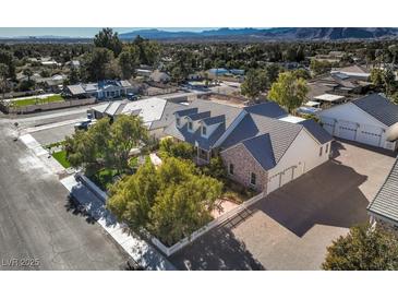 An inviting home with a brick driveway, mature trees, white picket fence, and a backdrop of scenic mountain views at 5110 N Valadez St, Las Vegas, NV 89149