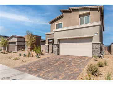 Two-story house with beige exterior, stone accents, and a paved driveway at 230 Palisade Falls Ave, Henderson, NV 89015