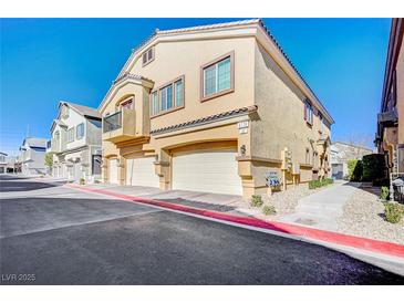 Inviting two-story townhome with attached garages, complemented by desert landscaping and a bright blue sky at 4710 Frasers Owl Ave # 103, North Las Vegas, NV 89084