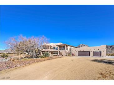 Two-story home with stucco exterior, attached garage, and desert landscaping at 4780 Mack Ct, Pahrump, NV 89060