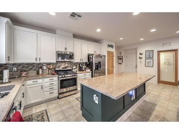 Modern kitchen with white cabinets, stainless steel appliances, large island, and stylish tile flooring at 6733 Violet Bluff Ct, North Las Vegas, NV 89084