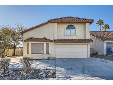 Tan two-story house with tile roof, two-car garage, and desert landscaping at 8633 Portofino Ct, Las Vegas, NV 89117