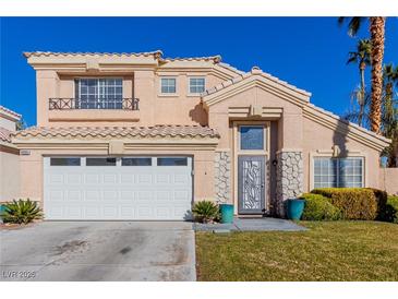 Two-story house with beige exterior, white garage door, and landscaped lawn at 8986 Lillyhammer Ct, Las Vegas, NV 89147