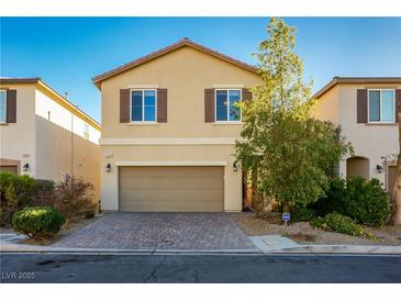 Two-story house with tan exterior, brown garage door, and landscaped front yard at 5684 Bishop Flowers St, Las Vegas, NV 89130