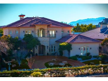Luxury two-story home with a terracotta tile roof, fountain, and mountain views at 9513 Verlaine Ct, Las Vegas, NV 89145