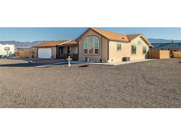 Beige house with a gravel driveway, attached garage, and landscaping at 2300 W Mielzynski Way, Pahrump, NV 89048