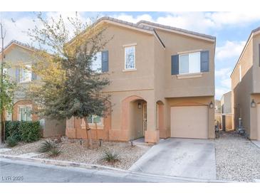 Two-story house with beige exterior, attached garage, and landscaping at 4129 Chamisa Cove St, Las Vegas, NV 89115