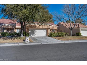 Tan two-story home with a red tile roof, attached garage, and landscaped front yard at 8608 Millsboro Dr, Las Vegas, NV 89134