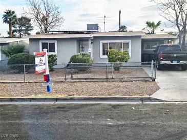 Ranch style home with gray exterior, chain link fence, and small front yard at 1920 Walnut Ave, Las Vegas, NV 89101