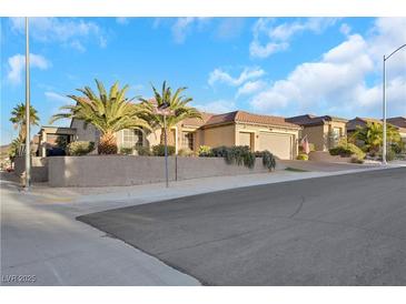 Single-story house with tan exterior, three-car garage, and palm trees at 2080 Twin Falls Dr, Henderson, NV 89044