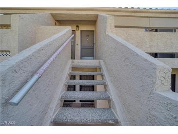 Inviting condo exterior featuring textured walls, a stairway, and the entrance to unit 118 at 3791 Desert Marina Dr # 118, Laughlin, NV 89029