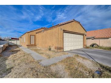 Tan house with a white garage door and a small front yard at 4496 Arlington Park Ct, Las Vegas, NV 89110