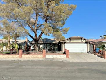 Ranch style home with brick facade, mature tree, and attached garage at 6402 Agua Dr, Las Vegas, NV 89103