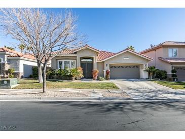 Tan colored house with a two-car garage and palm trees at 2132 Timber Rose Dr, Las Vegas, NV 89134