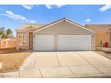 Tan two-car garage home with a landscaped yard at 861 Zinnia Cir, Henderson, NV 89015