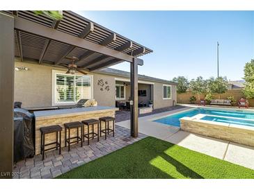 Outdoor kitchen, pool, spa, and pergola create a relaxing backyard oasis at 9820 Maiden Pink Ave, Las Vegas, NV 89149