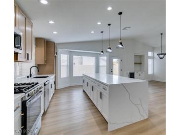 Modern kitchen with white cabinets, large island, and stainless steel appliances at 7812 Desert Candle Way, Las Vegas, NV 89128