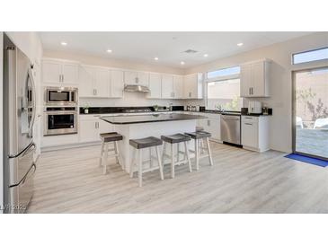 Bright kitchen features a large island with seating, stainless steel appliances and white cabinets at 8749 Black Cordon Rd, Las Vegas, NV 89139