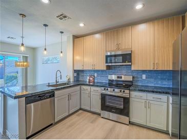 Modern kitchen features stainless steel appliances and blue tile backsplash at 1510 Fieldbrook St, Henderson, NV 89052