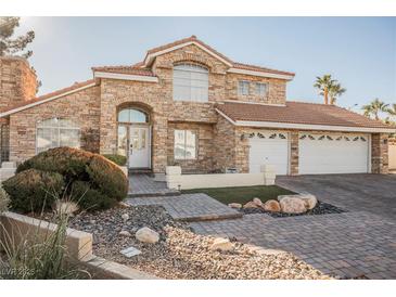 Two-story house with stone exterior, three-car garage, and landscaped front yard at 2000 White Falls St, Las Vegas, NV 89128