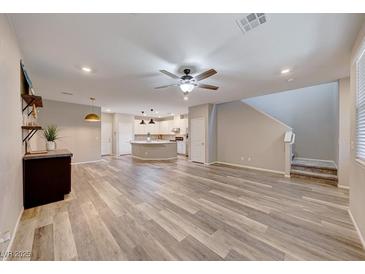 Open living room with hardwood floors, island kitchen, and modern staircase at 2844 Alenga St, Henderson, NV 89044