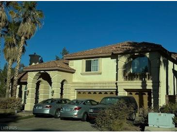 Two-story house with arched entryway and attached two-car garage, parked cars in driveway at 7616 Gossamer Wind St, Las Vegas, NV 89139