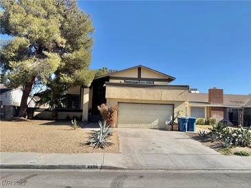 House exterior featuring a two-car garage and mature landscaping at 4406 Flowerdale Ct, Las Vegas, NV 89103