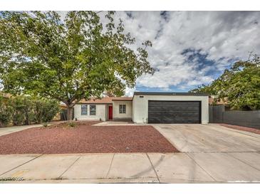 Updated single-story home with a red door, new landscaping, and a dark gray garage door at 145 Hancock St, Las Vegas, NV 89110