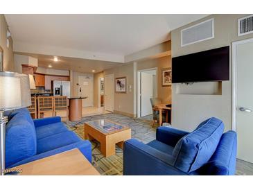 Spacious living room featuring a blue sofa and chairs, coffee table, and a large flat-screen TV at 211 E Flamingo Rd # 615, Las Vegas, NV 89169