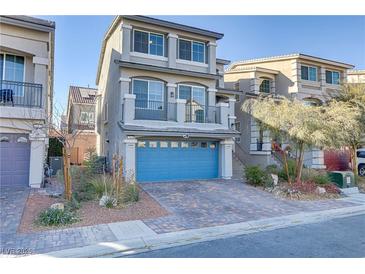 Two-story home with gray siding, blue garage door, and landscaped front yard at 7075 Jasper Hill Way, Las Vegas, NV 89118