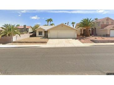 Beige house with two-car garage and desert landscaping at 707 Arrowhead Trl, Henderson, NV 89002