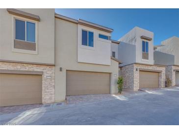 Modern townhome exterior with attached garage and stone accents at 11935 Glide Reflection Ave, Las Vegas, NV 89138