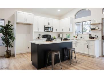 Bright kitchen with white cabinetry, island with bar stool seating, and modern stainless steel appliances at 6304 Tanzanite Ave, Las Vegas, NV 89130