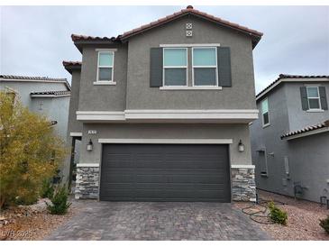 Two-story house with gray siding, dark gray garage door, and paved driveway at 7672 Lush Oasis Ave, Las Vegas, NV 89113