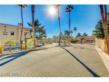 View of the community entrance with secured gate and desert landscaping at 2983 Juniper Hills Blvd # 102, Las Vegas, NV 89142