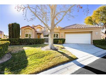 Tan two-story house with a white garage door and landscaped lawn at 7943 Harbour Towne Ave, Las Vegas, NV 89113