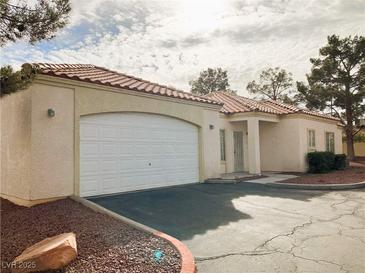 Tan stucco house with tile roof, white garage door, and landscaping at 1900 N Torrey Pines Dr # 132, Las Vegas, NV 89108