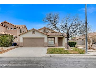 Single-story house with tan exterior, brown garage door, and a tree in front at 3708 Penny Cross Dr, North Las Vegas, NV 89032