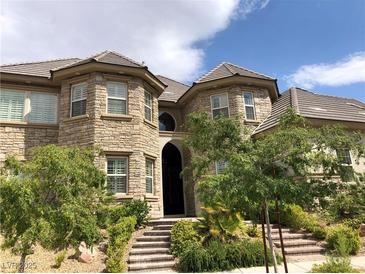 Two-story stone house with a gabled roof, multiple windows, and landscaping at 768 Tozzetti Ln, Henderson, NV 89012